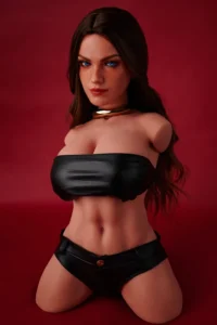 ULW 663# Emma: This front-view photo captures the doll's detailed torso featuring striking blue eyes and long wavy dark hair, wearing a black leather bandeau top that highlights her fair, smooth realistic skin and full curves against a red backdrop.
